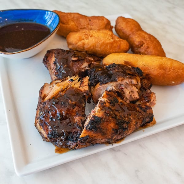 Peppas Jerk Chicken with a side of fried dumplings and a bowl of dipping sauce.