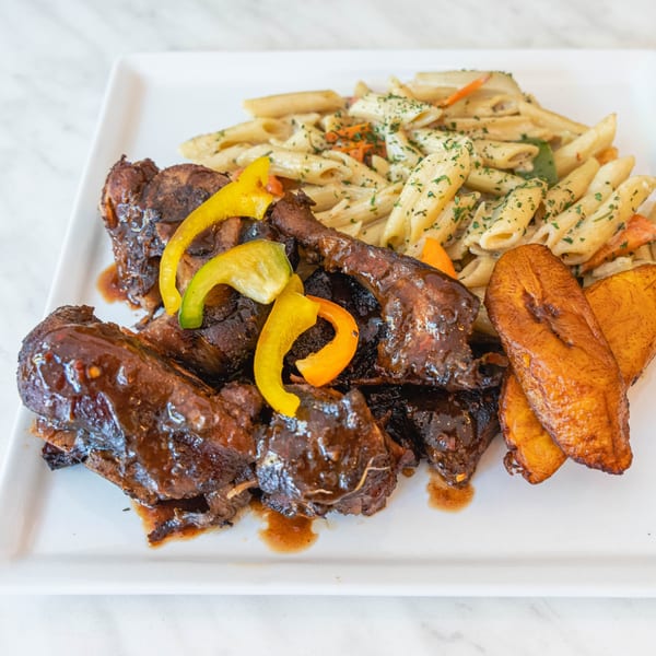 Peppas Jerk Chicken with penne pasta, bell peppers, and fried plantains on a white plate.